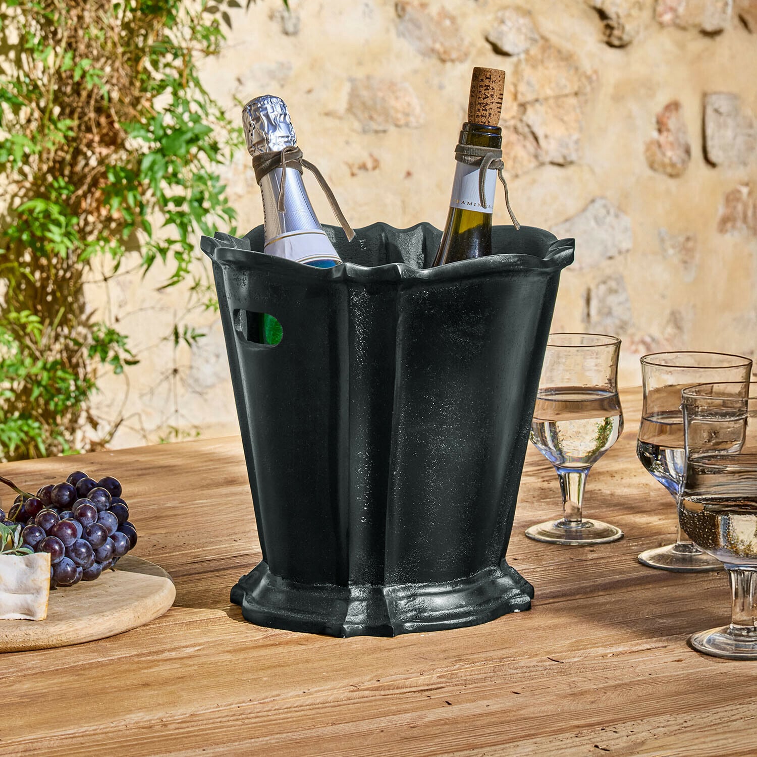 Enfriador de bebidas Trévaux Cubitera de metal negra con dos botellas de vino sobre mesa de madera en exterior