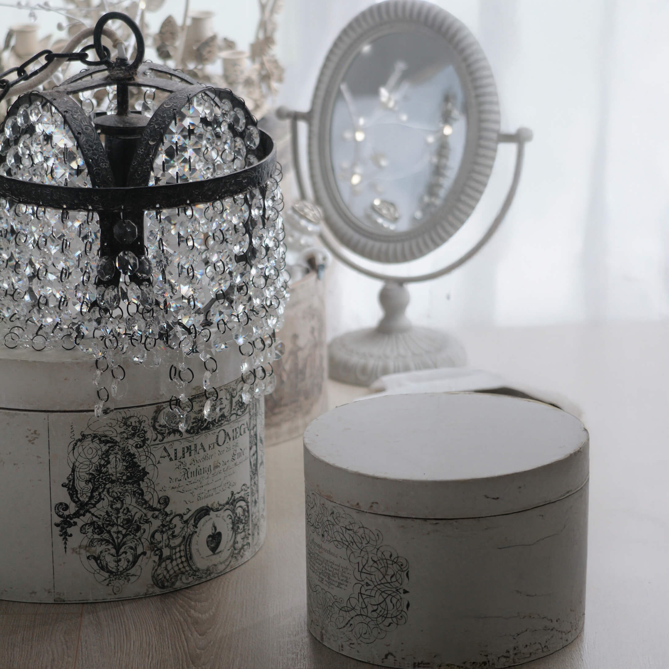 Lámpara de cristal con estructura metálica negra sobre caja vintage blanca con ornamentos