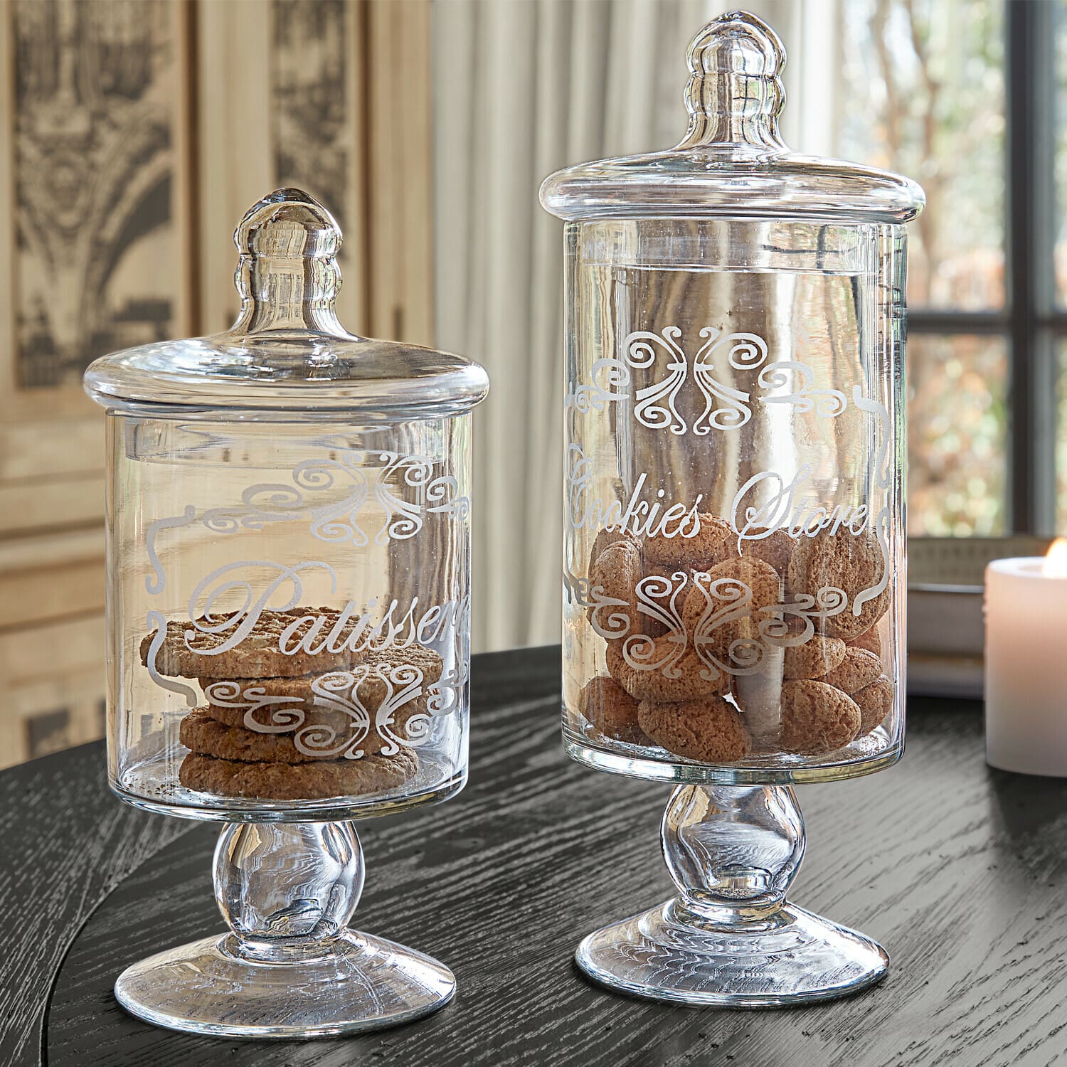 Set de 2 tarros Suzie Tarros de cristal con tapas y texto decorativo llenos de galletas sobre mesa negra