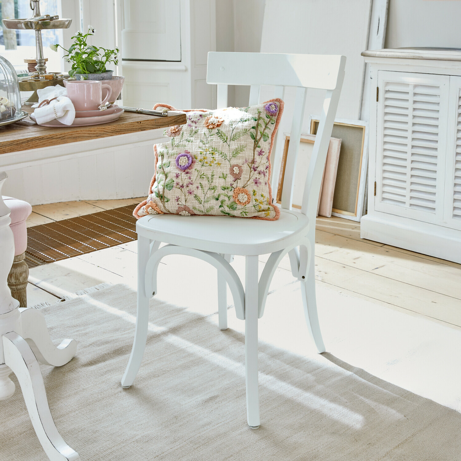 Silla Passigny Silla de madera blanca con cojín bordado con flores en un comedor luminoso y acogedor