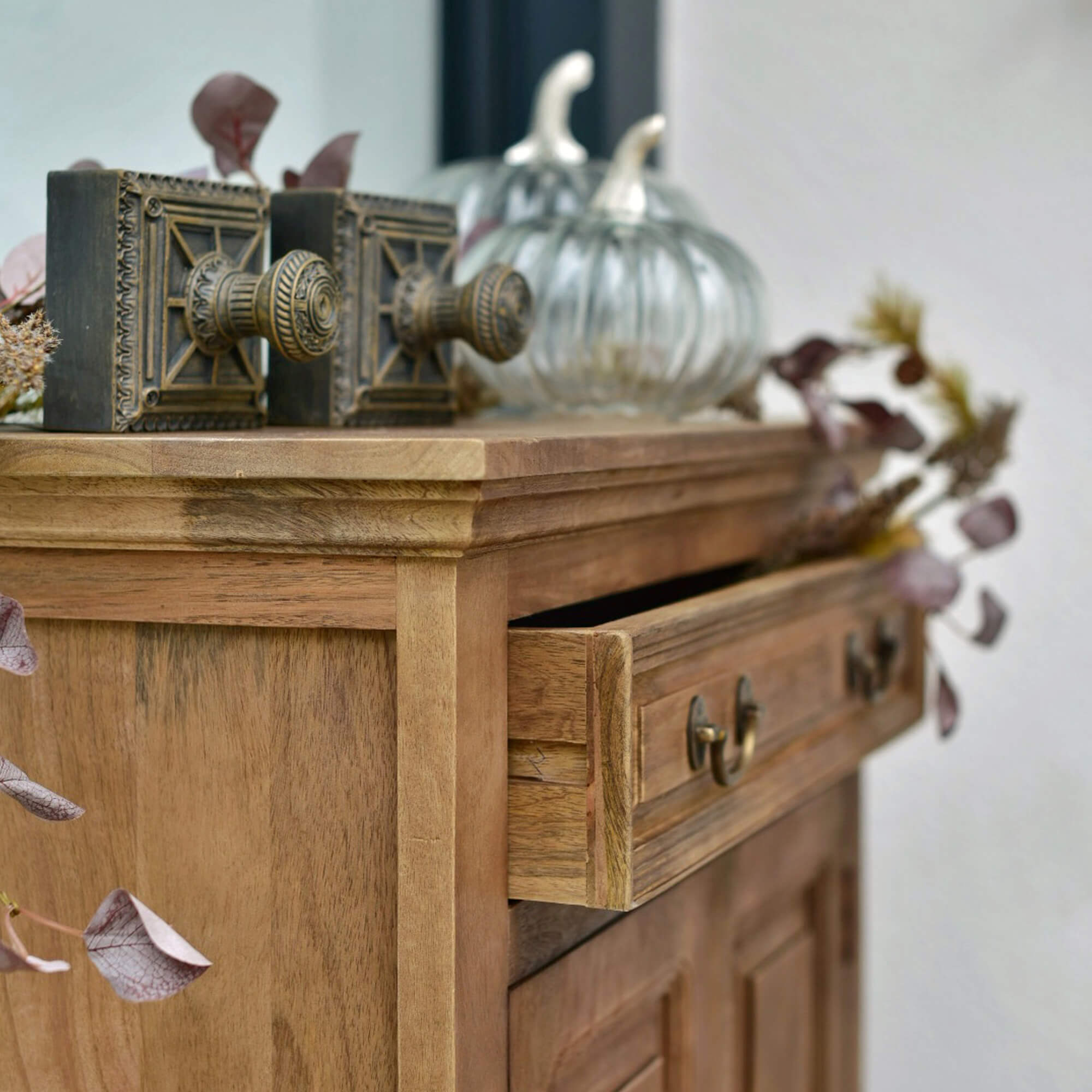 Cómoda de madera con cajón abierto, tiradores decorativos de latón y adornos de cristal en forma de calabaza