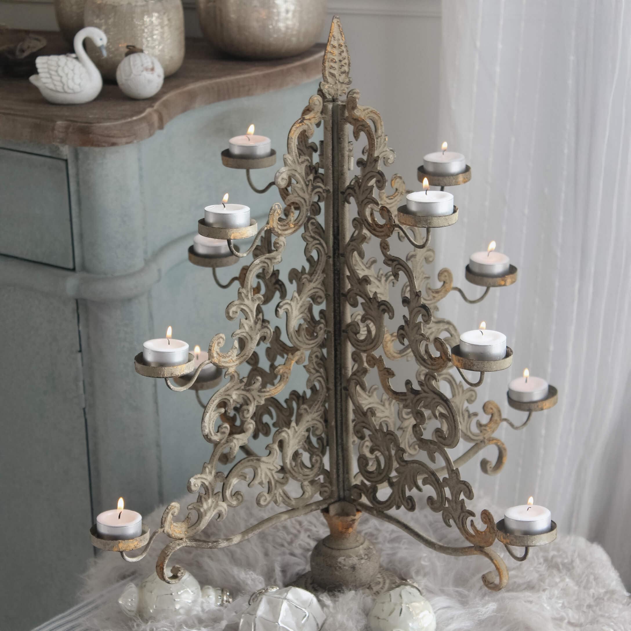 Candelabro metálico dorado envejecido con diseño calado y velas de té encendidas