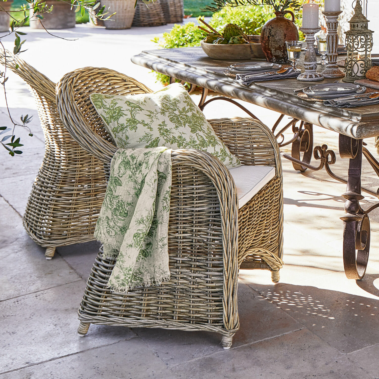 Sillón de ratán natural con cojín y manta verde para terraza o jardín exterior