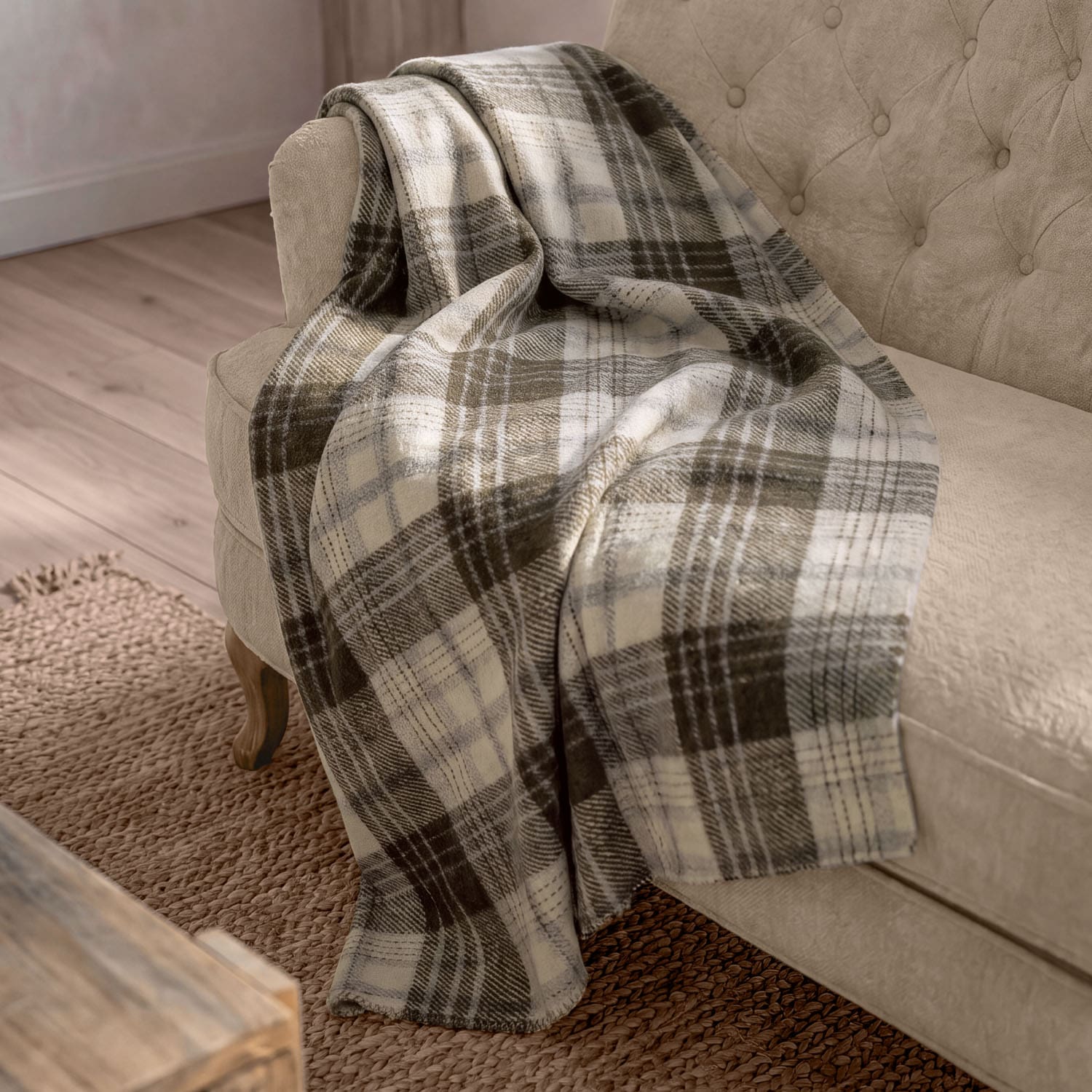 Manta suave de cuadros en tonos beige y marrón sobre un sofá beige en salón