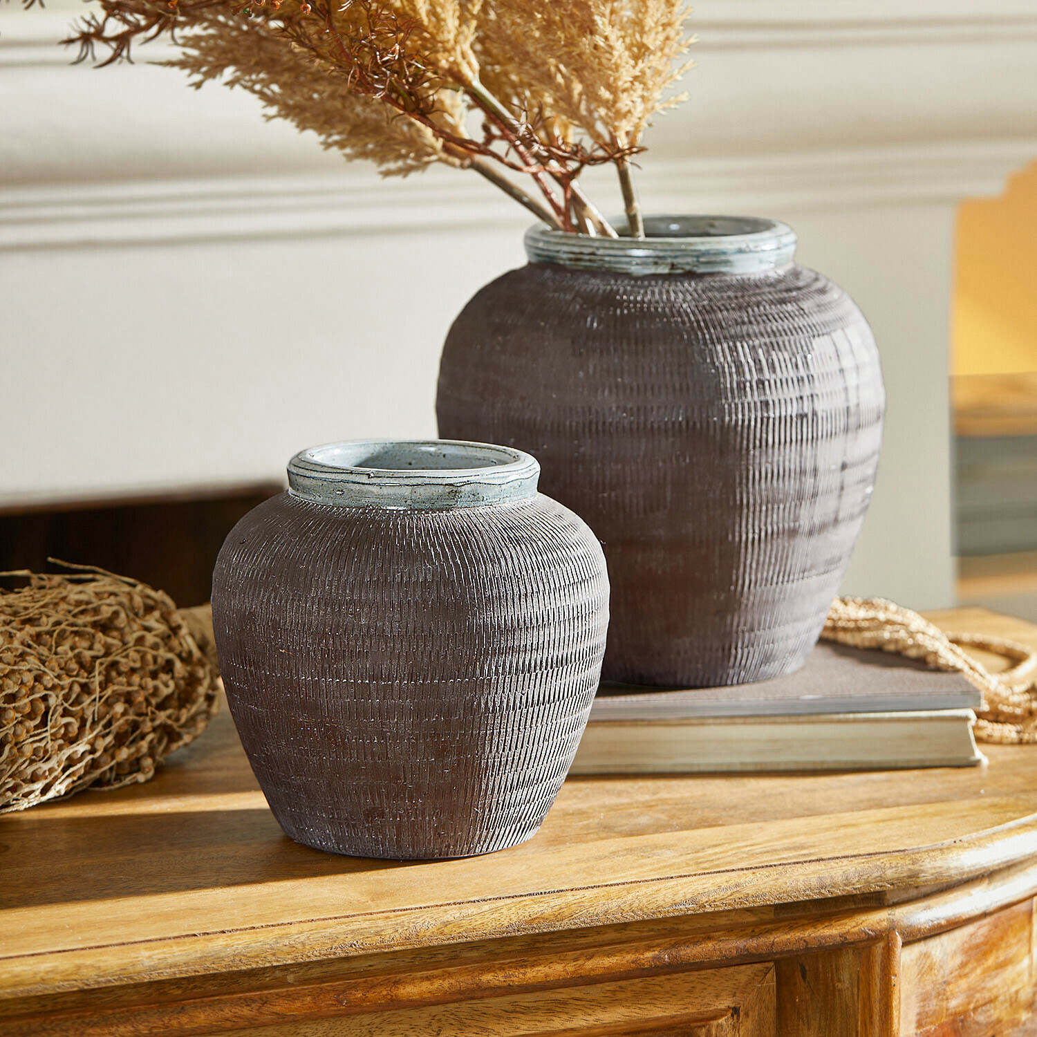 Set de 2 jarrones Calverna Dos jarrones decorativos de cerámica marrón sobre mesa de madera con plantas secas