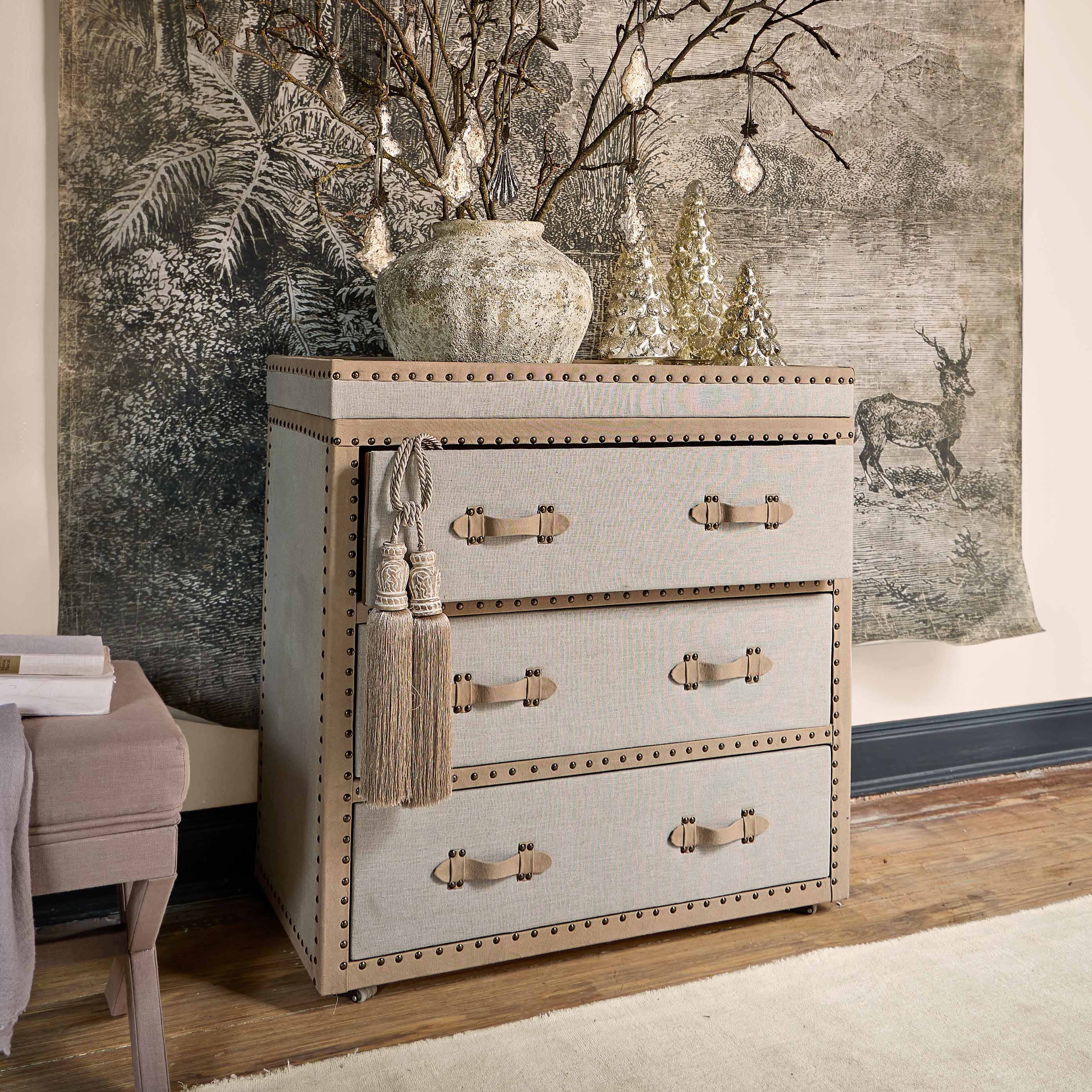 Cómoda beige de tela con tiradores decorativos y borlas, estilo vintage para salón