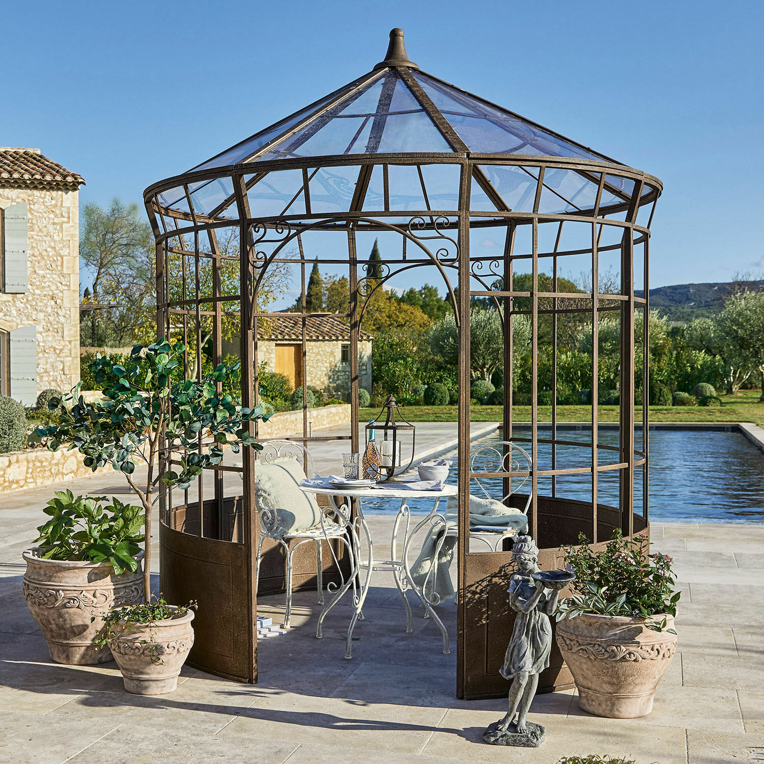Pabellón Murillo Pérgola decorativa de metal color óxido con mesa blanca y sillas en terraza junto a piscina