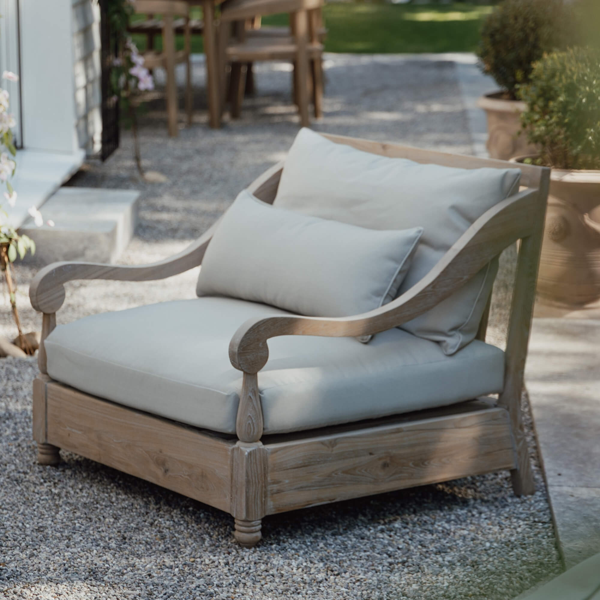 Sofá de jardín de madera clara con cojines crema, muebles cómodos para terraza