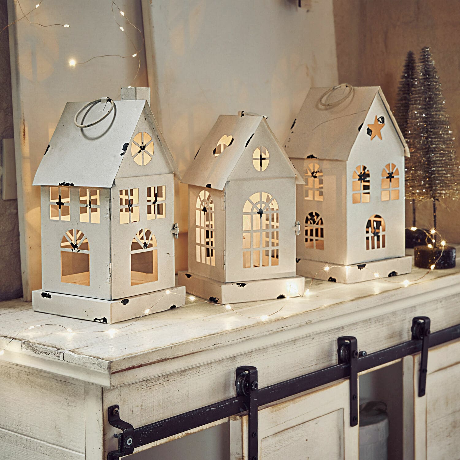 Set de 3 farolillos LED Village Conjunto de tres faroles metálicos blancos en forma de casa con ventanas recortadas y luces festivas