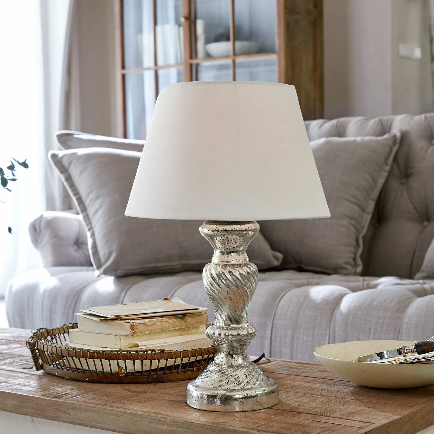 Lámpara de mesa Hazel Lámpara de mesa con pantalla blanca y base plateada sobre mesa de madera en sala de estar