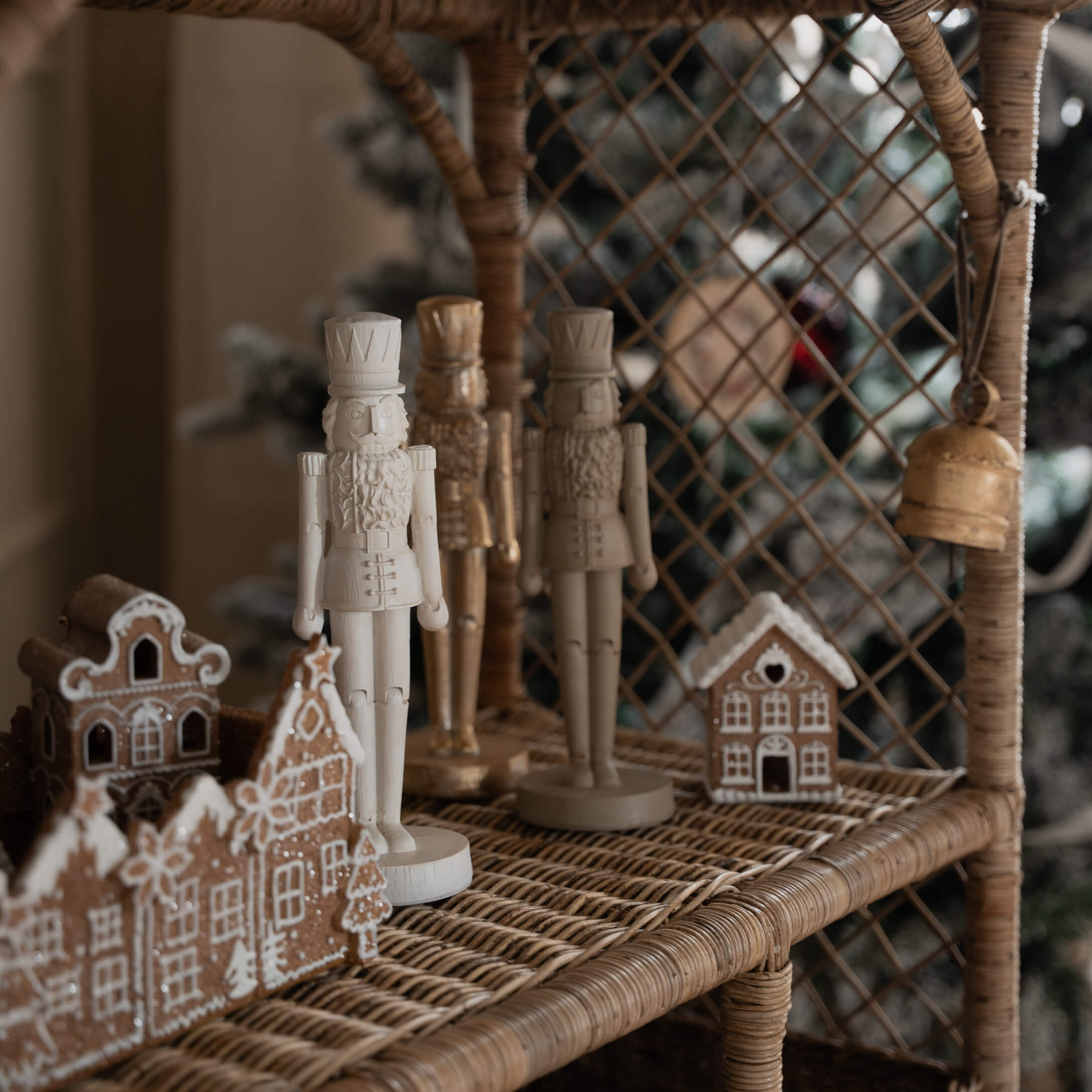 Figuras de madera de cascanueces blancas y beige en estantería de mimbre con casas de jengibre