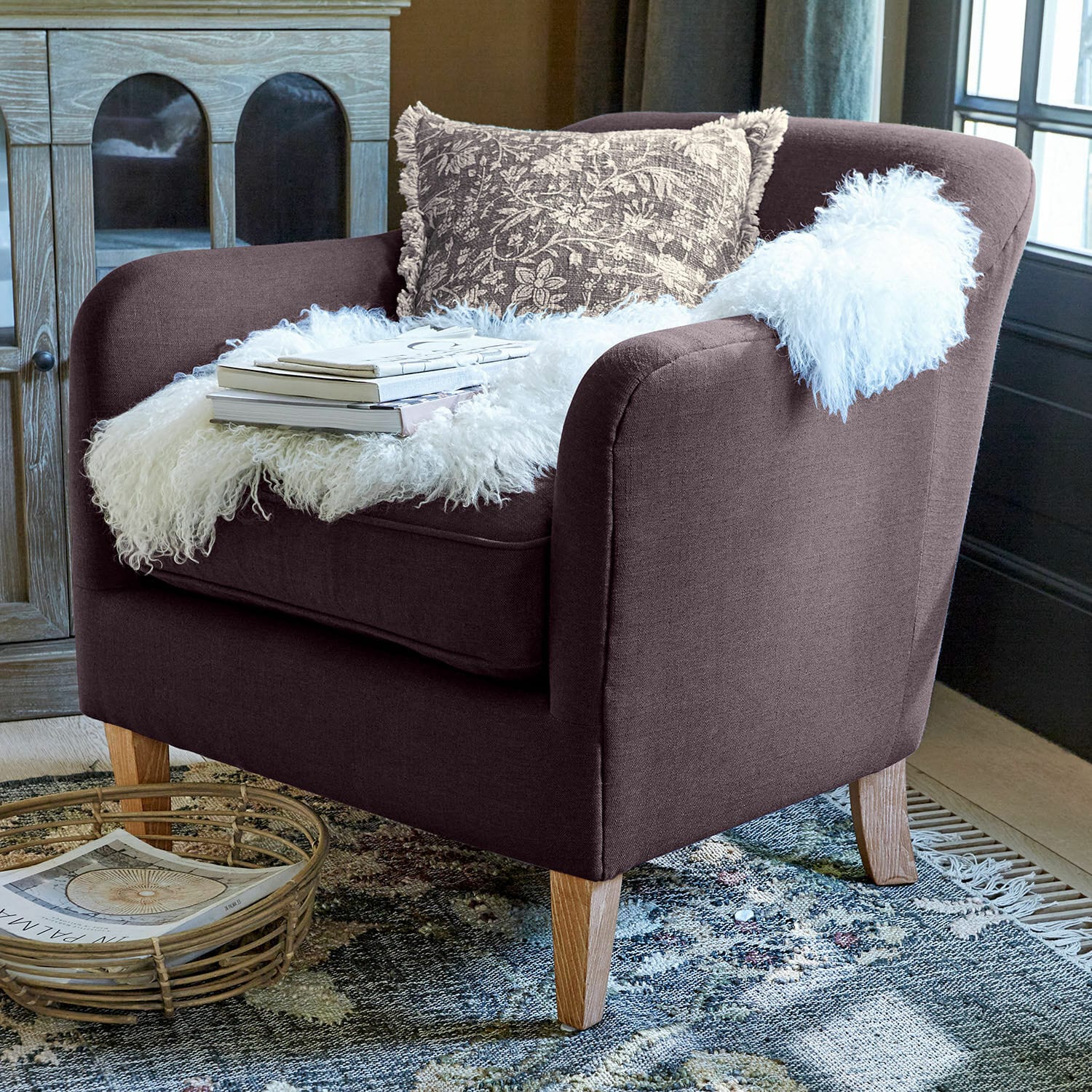 Sillón Jefferson Sillón tapizado marrón con patas de madera, decorado con manta blanca de piel sintética y cojín estampado