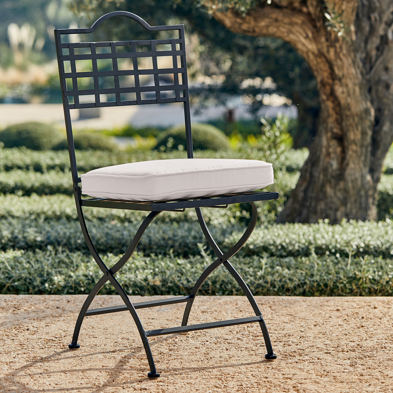 Silla de jardín de metal negro con cojín blanco, perfecta para muebles de exterior elegantes