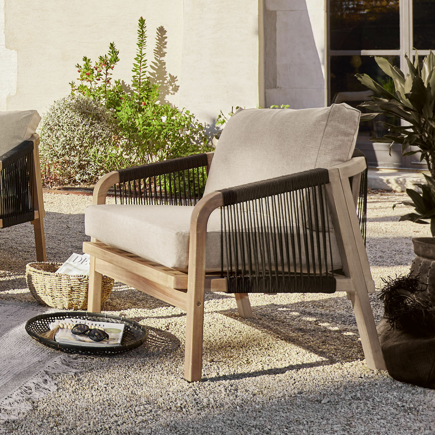 Sillón de jardín con cojín beige claro, estructura de madera y cuerdas negras, muebles de exterior
