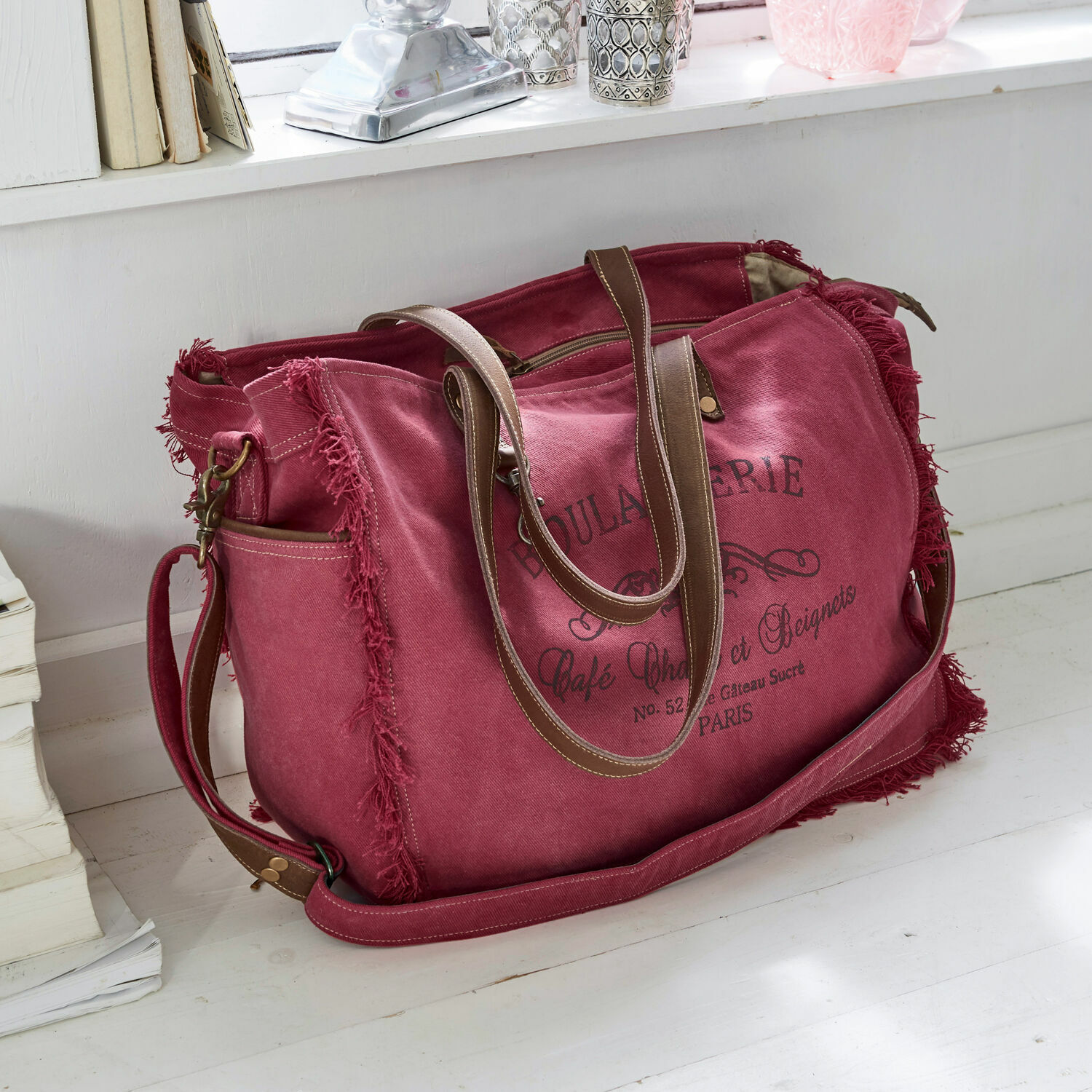 Bolso Anoush Bolsa de viaje de lona roja con asas marrones y estampado vintage sobre suelo blanco
