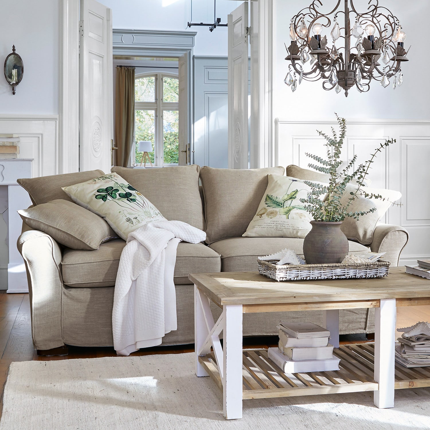 Sofá Long Beach Sofá beige de tela con cojines decorativos y mesa de centro de madera en sala luminosa