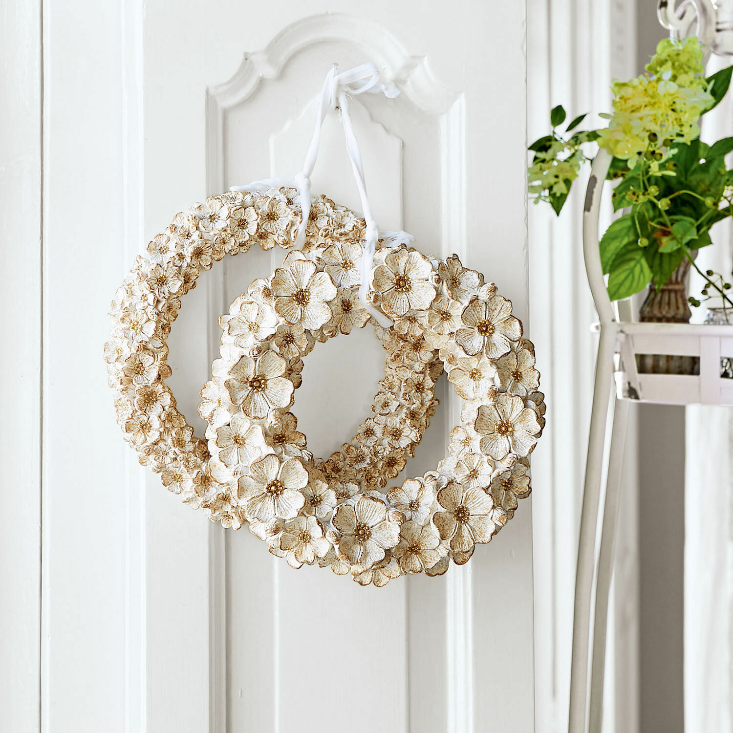 Set de 2 coronas Marie Corona decorativa de flores blancas con detalles beige colgada en puerta blanca