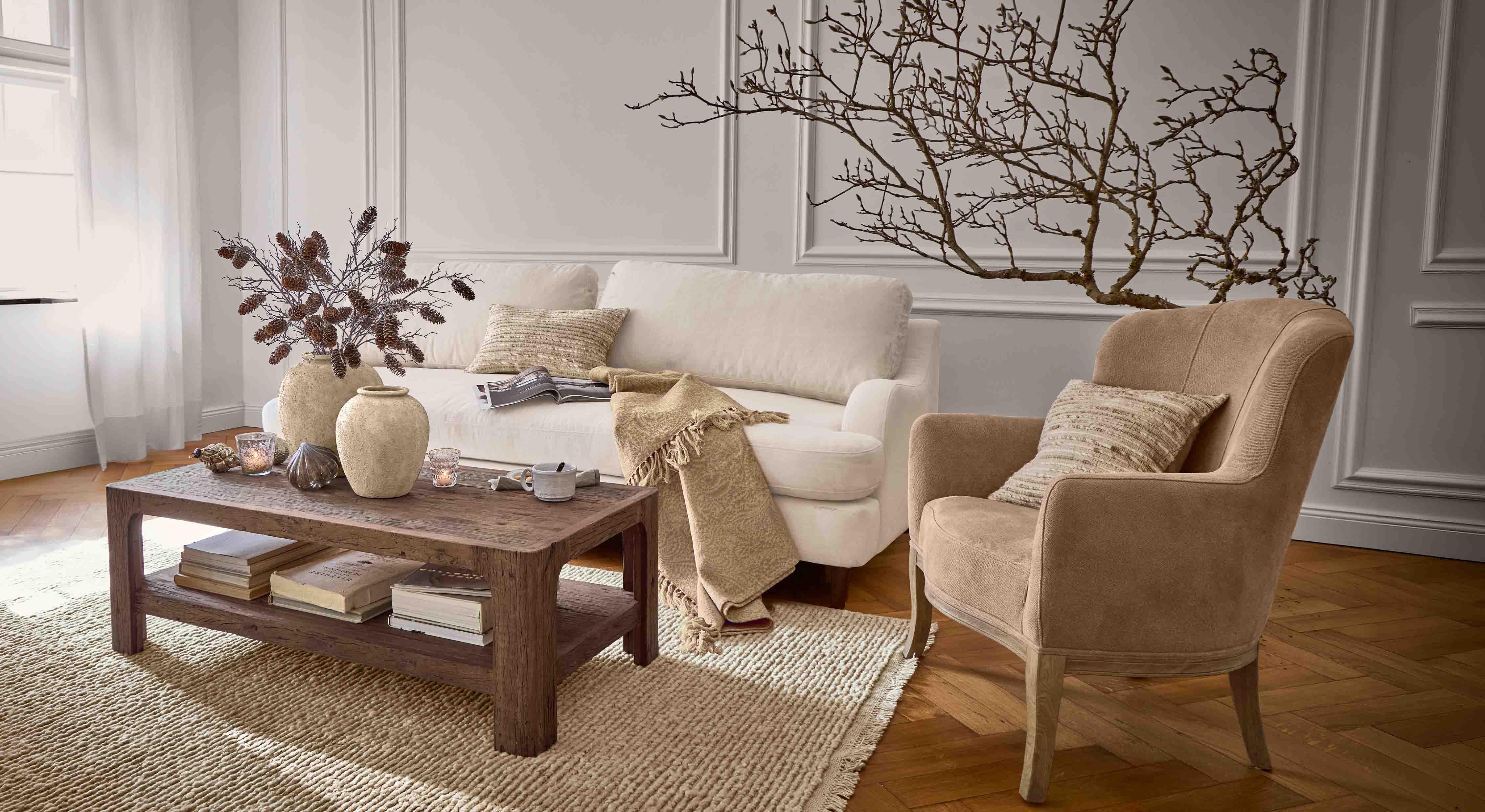Salón acogedor con sofá beige, sillón marrón y mesa de centro de madera sobre alfombra tejida