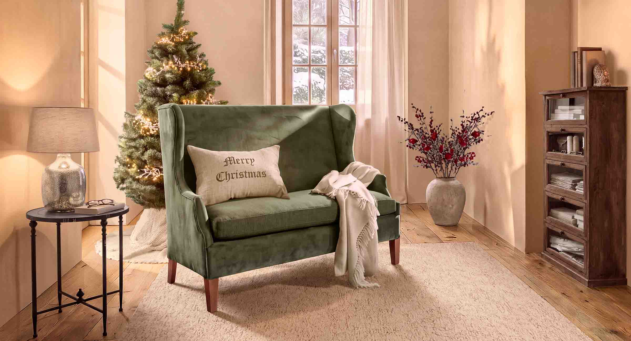Sofá verde de terciopelo con cojín Merry Christmas en salón acogedor con árbol de Navidad