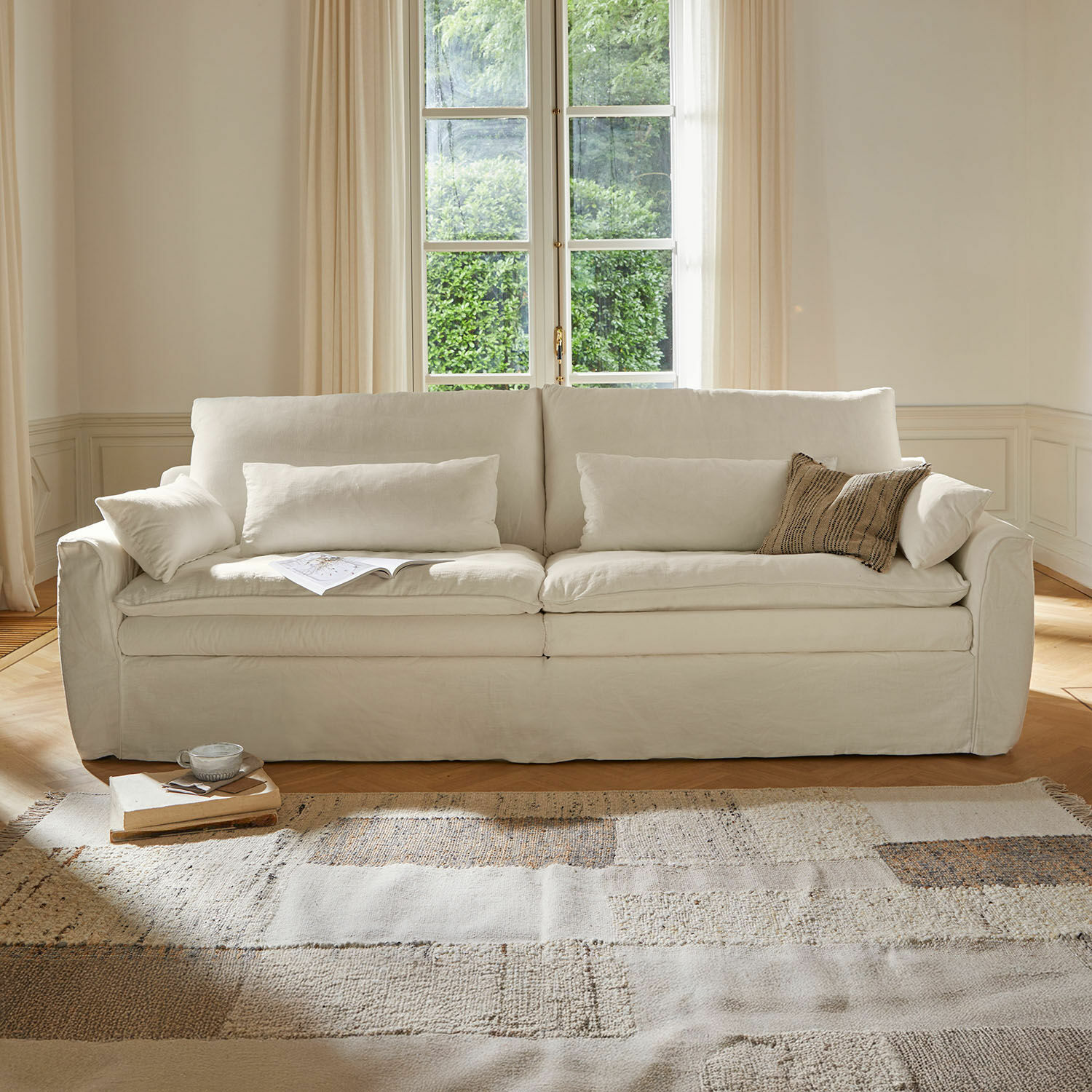 Sofá Dunhaven Sofá beige de tela con cojines y alfombra clara en salón acogedor y luminoso