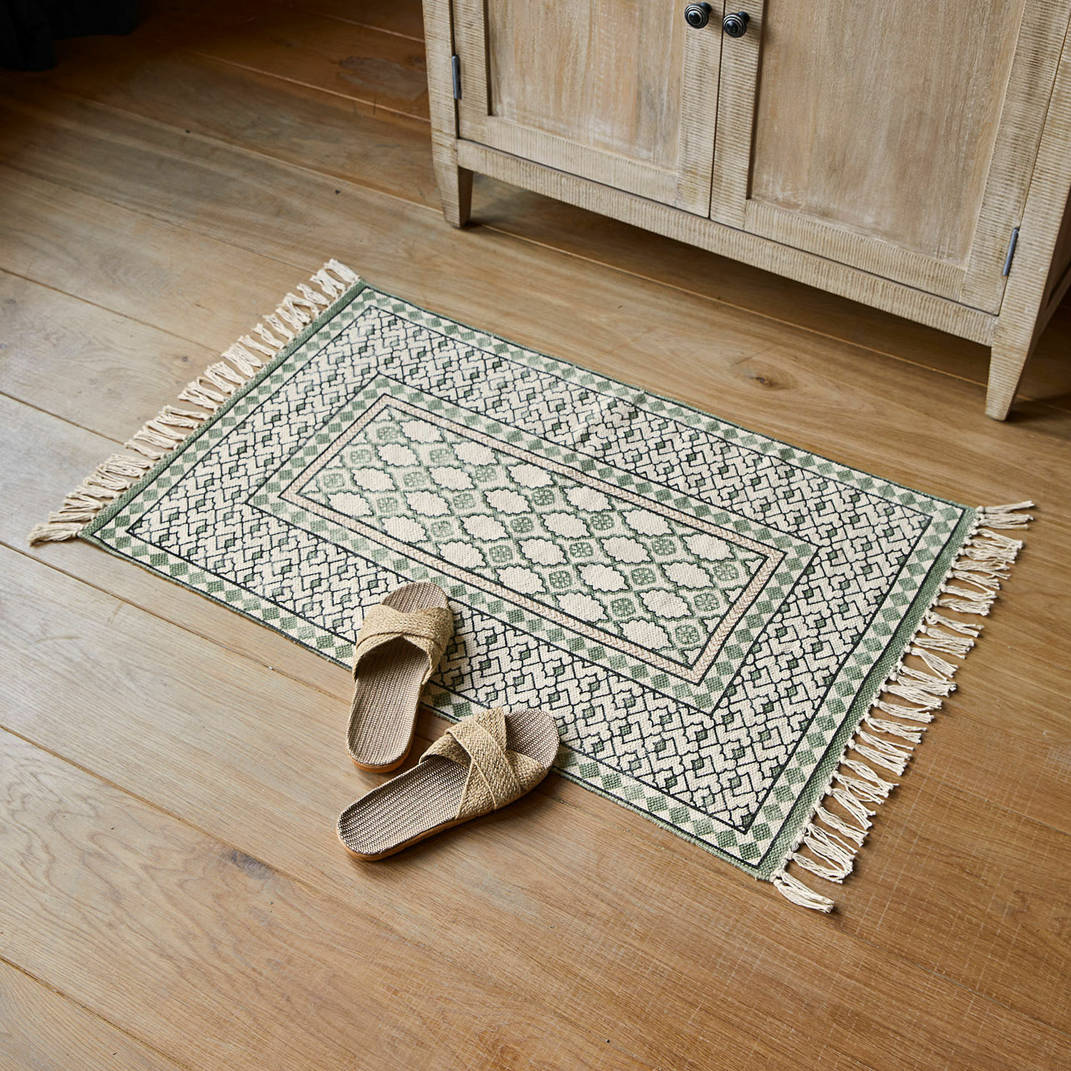 Alfombrilla de baño Vellantino Alfombra de algodón verde y crema con flecos sobre suelo de madera, decoración interior elegante