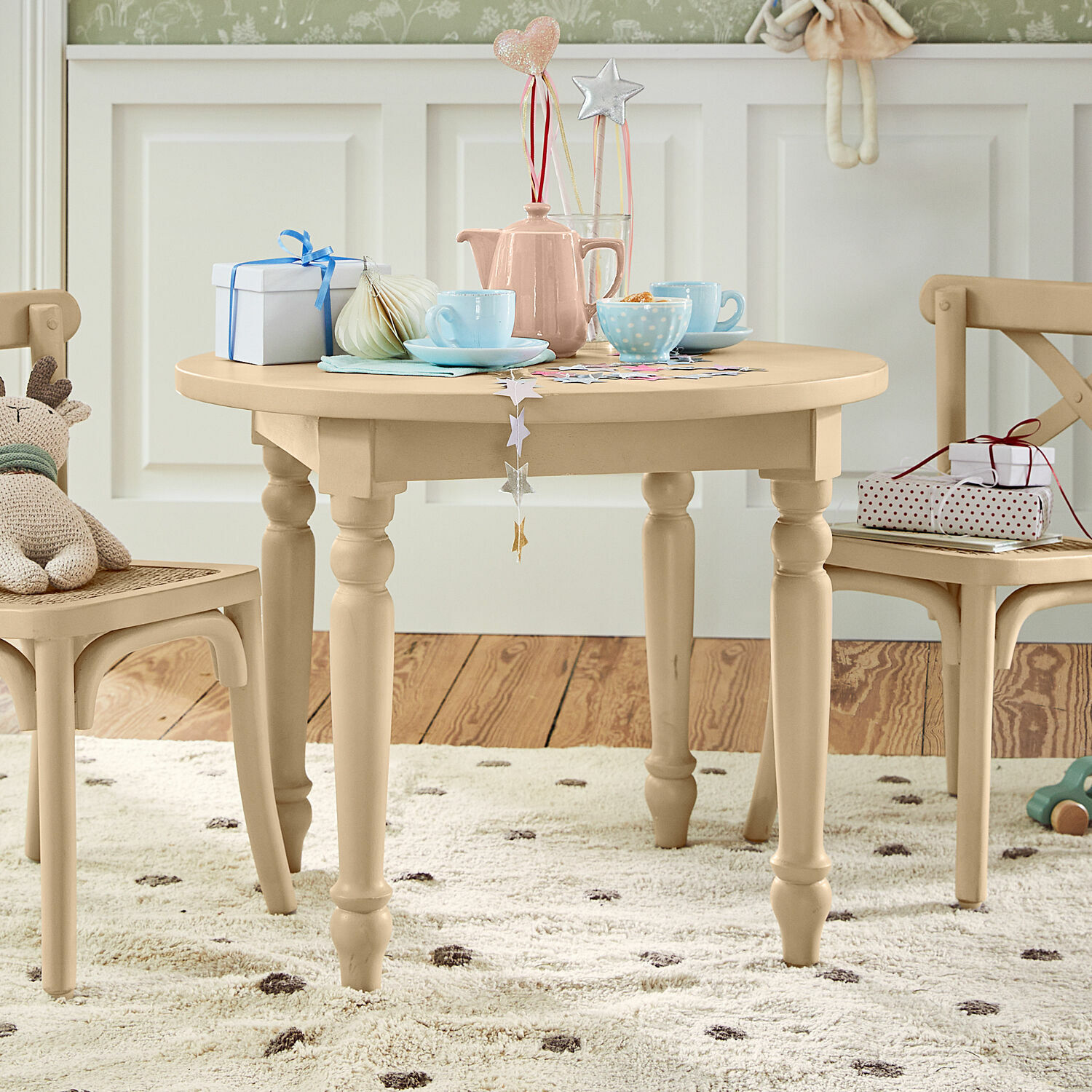 Mesa para niños Sourila Mesa redonda infantil de madera beige con decoraciones y juguetes sobre alfombra con puntos