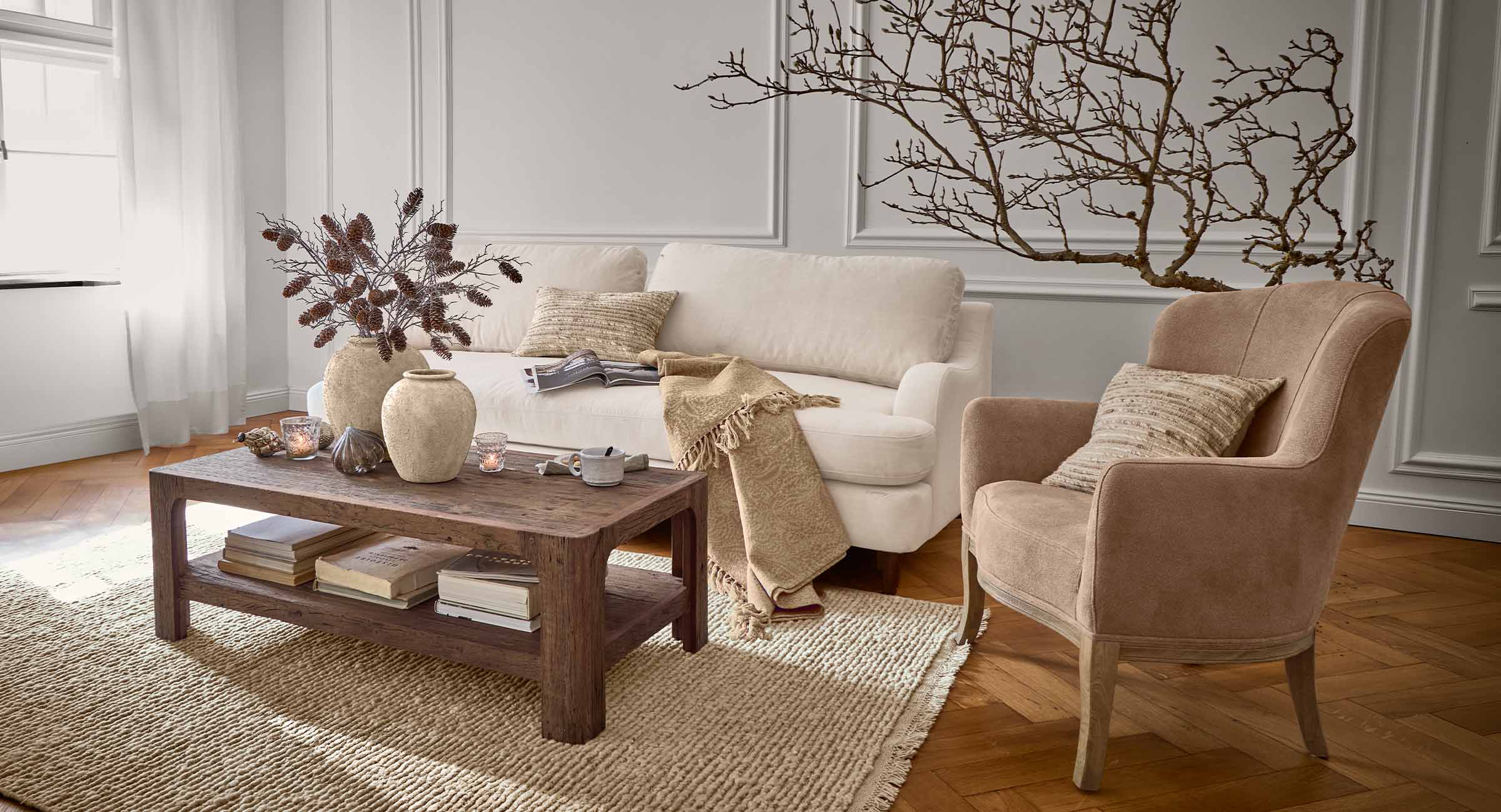 Salón acogedor con sofá beige, sillón marrón y mesa de centro de madera sobre alfombra de fibras naturales