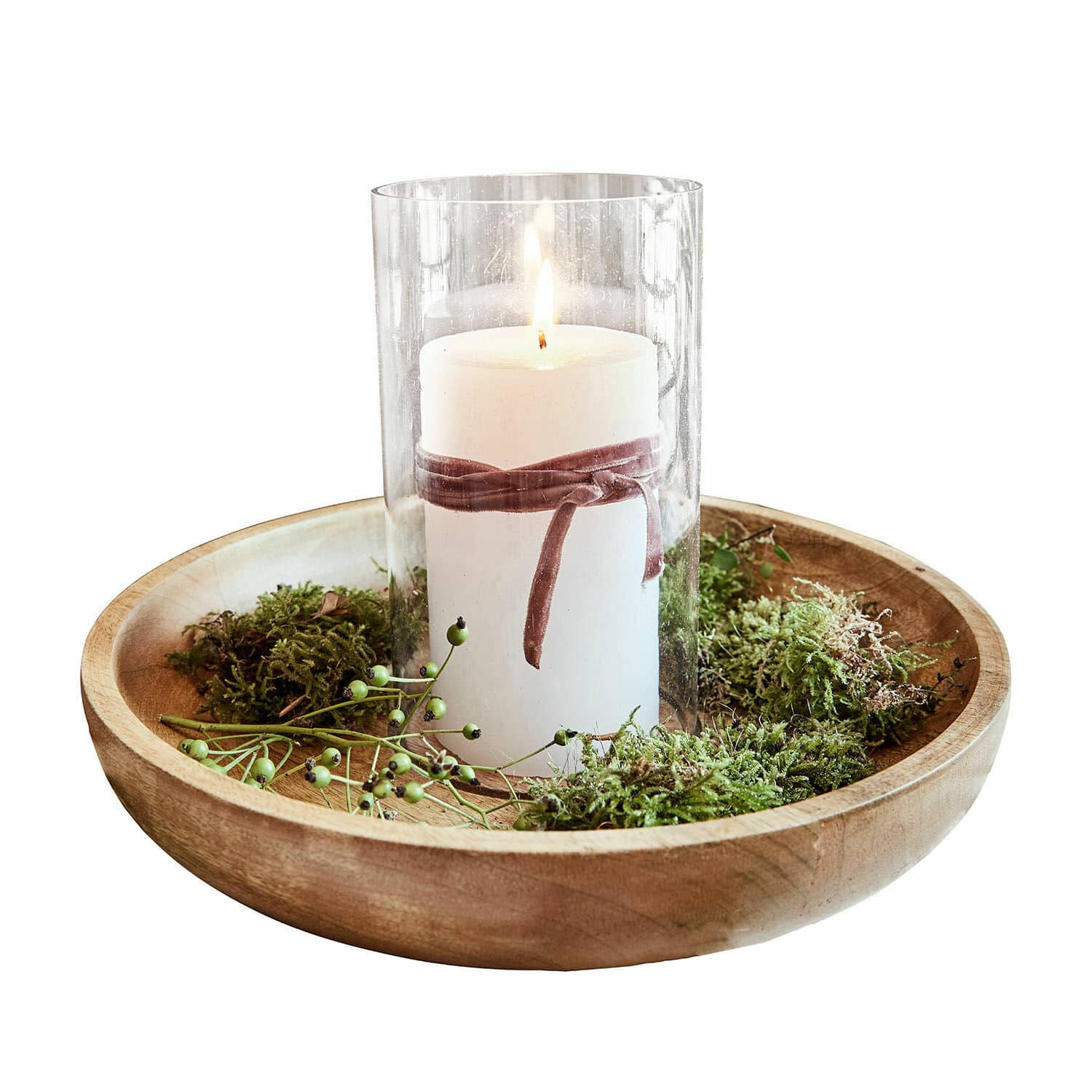 Vela blanca en vaso de cristal sobre bandeja de madera con musgo verde decorativo
