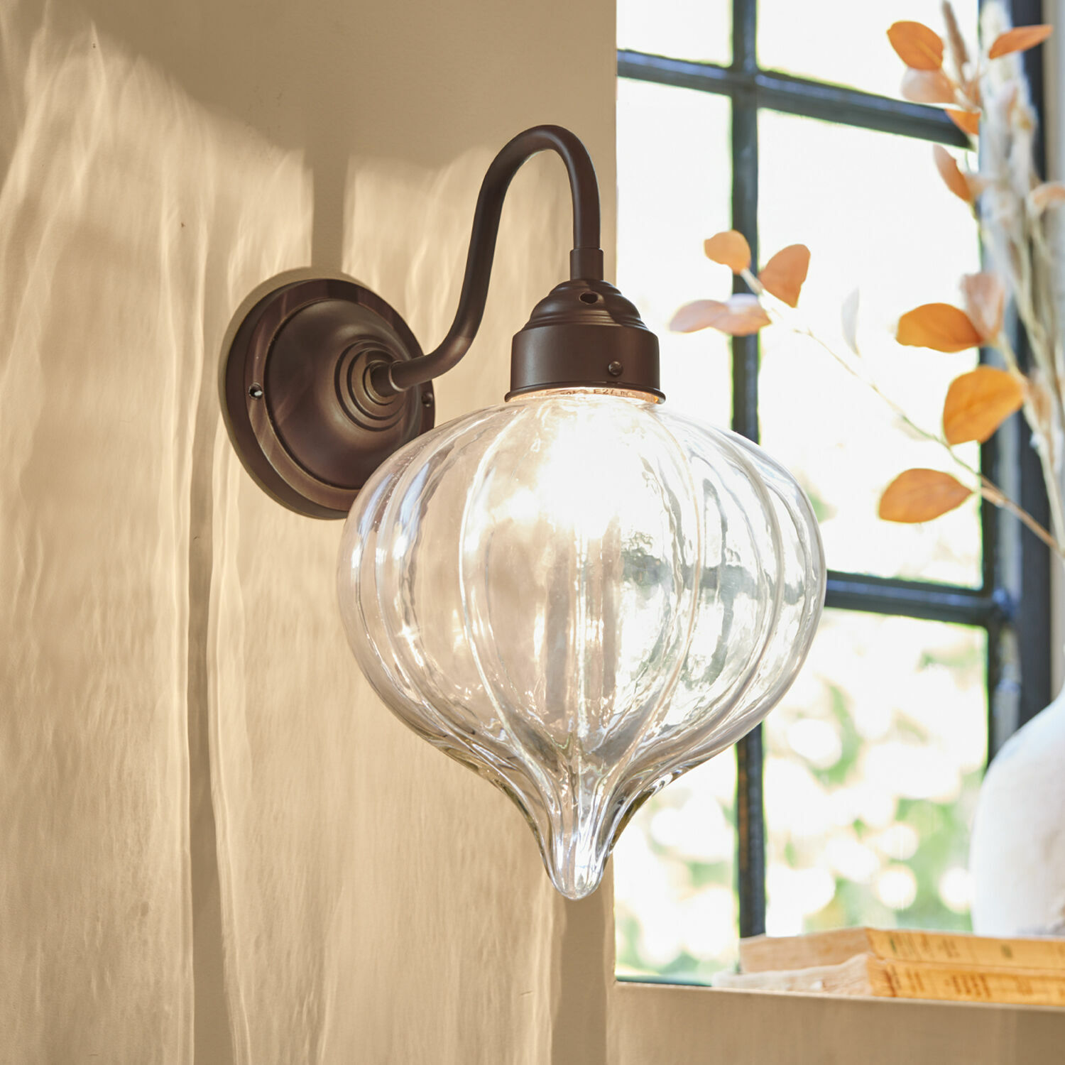Aplique de pared de vidrio transparente con soporte metálico marrón para decoración interior
