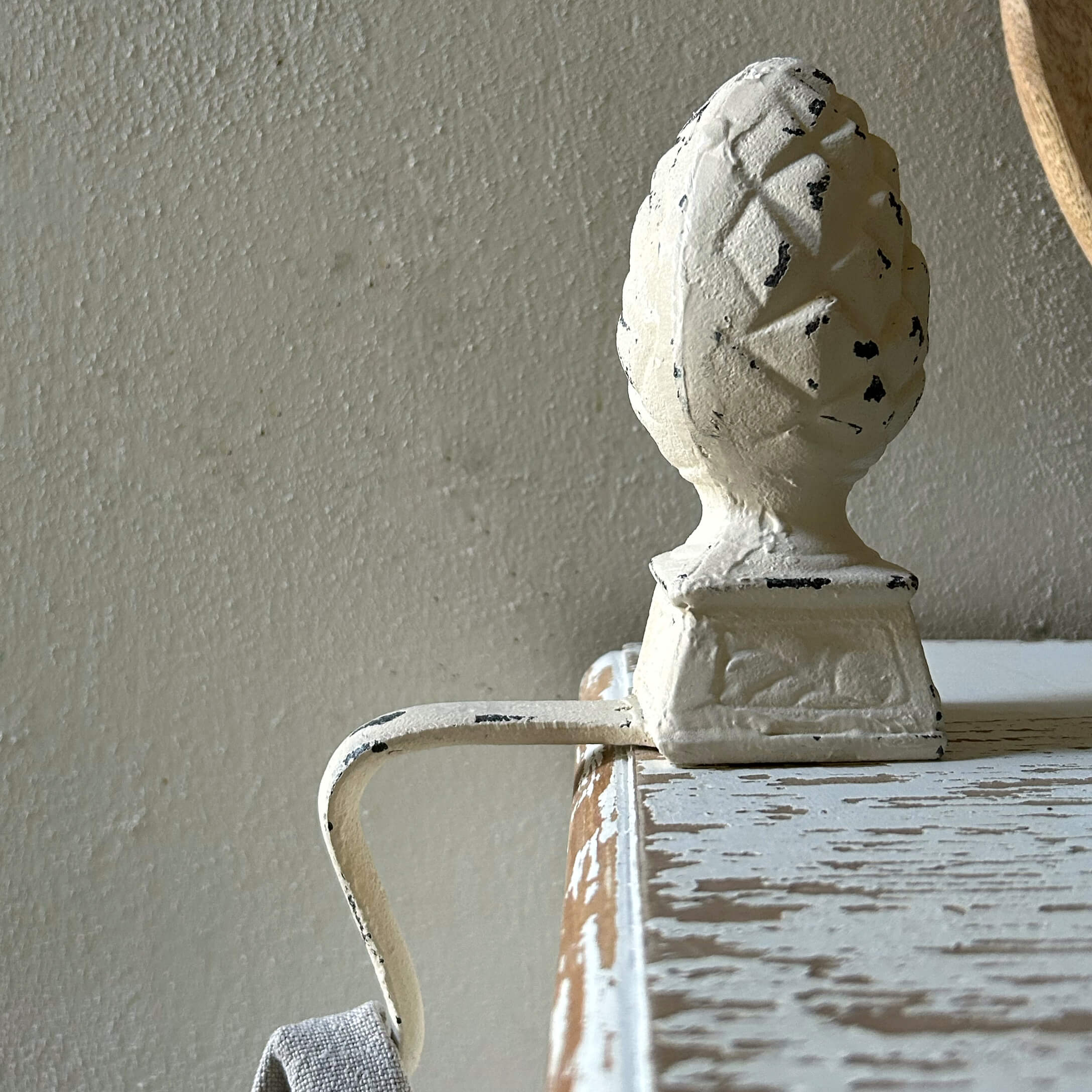 Tirador metálico blanco con adorno de piña en mueble de madera envejecida