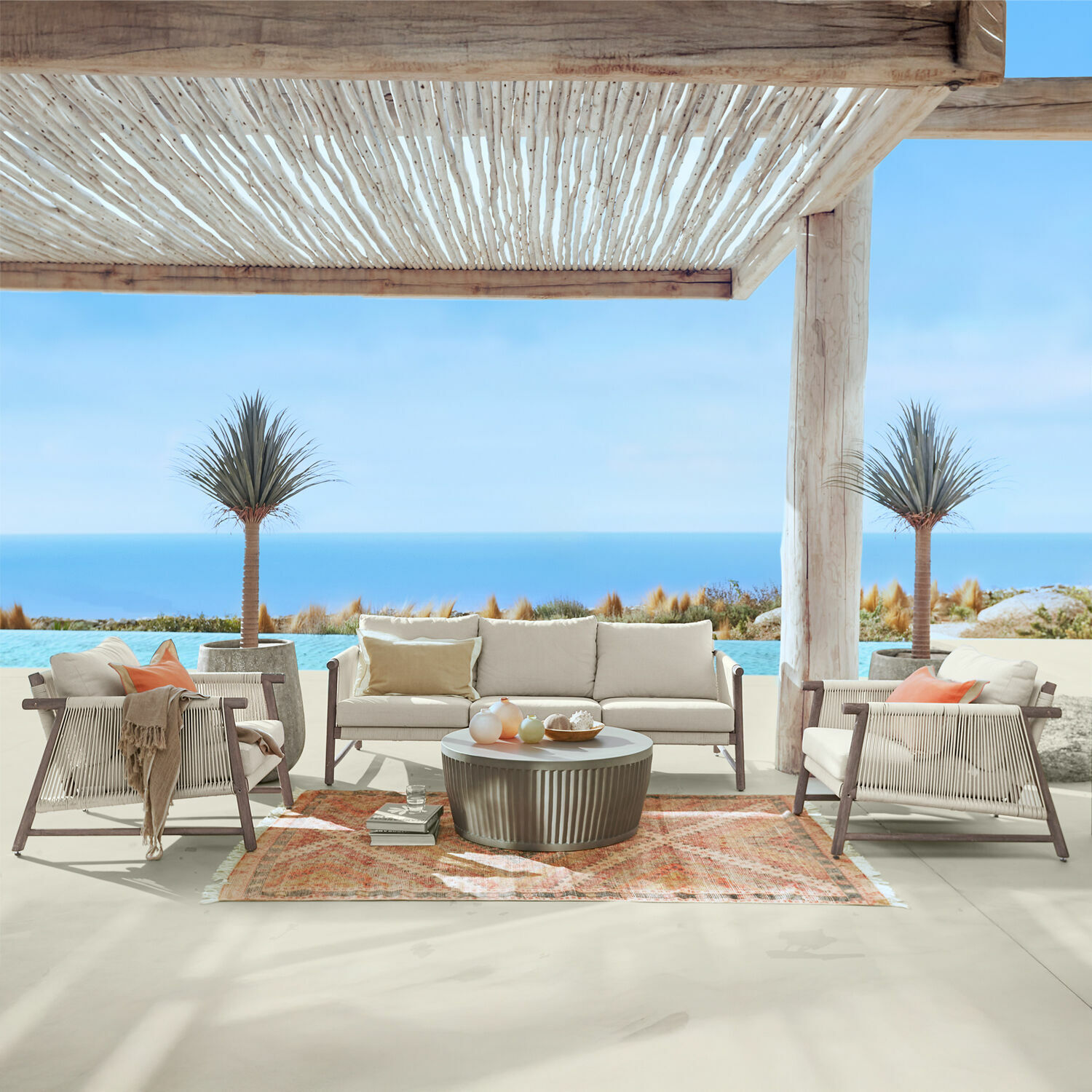 Grupo de asientos FSC®-100% Clarmontaine Conjunto de muebles de exterior con cojines beige y estructura de madera en terraza con vista al mar